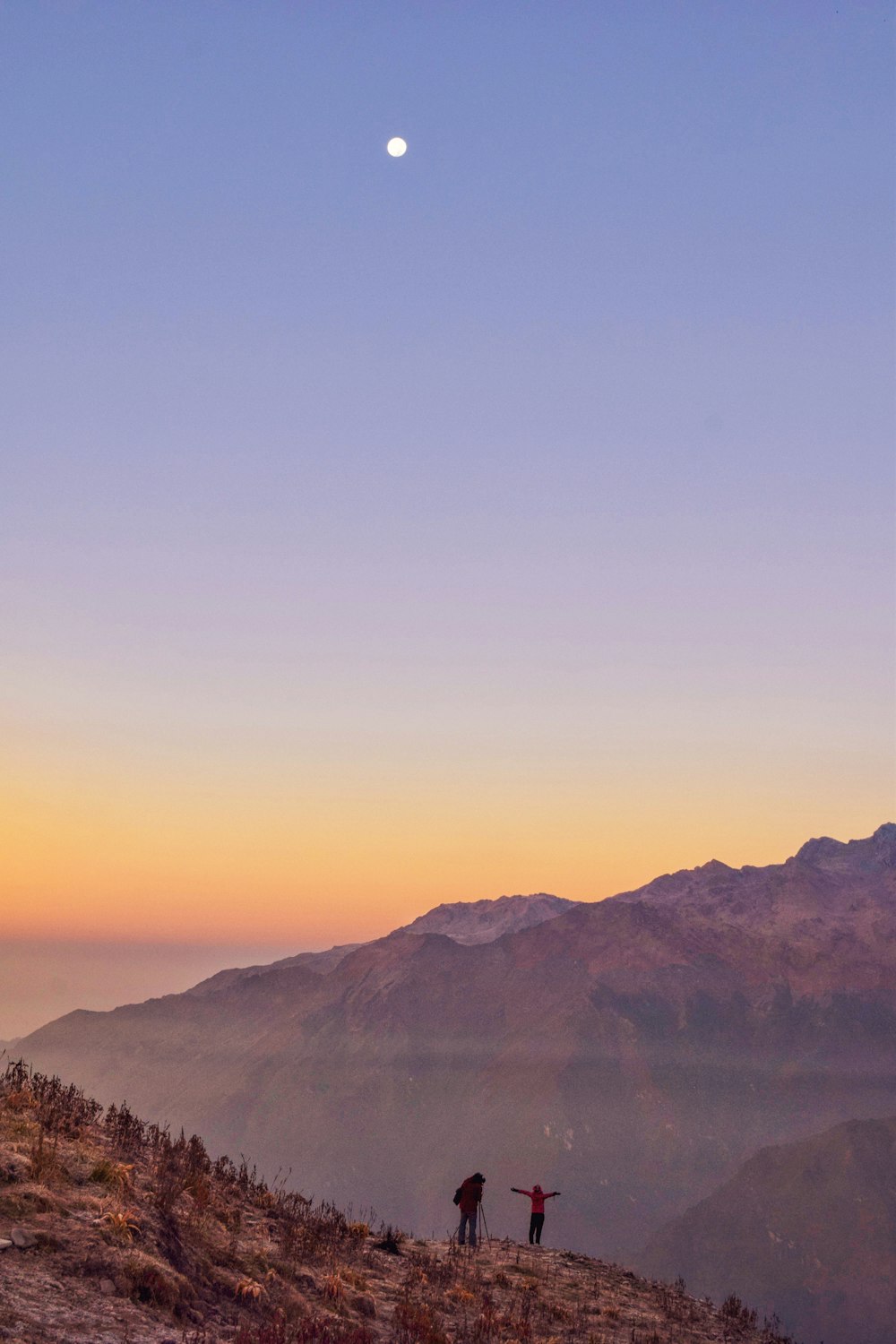 silhouette of two people standing on top of mountain during daytime