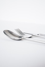 Elegant silverware set displayed on a polished wooden table with soft natural light.