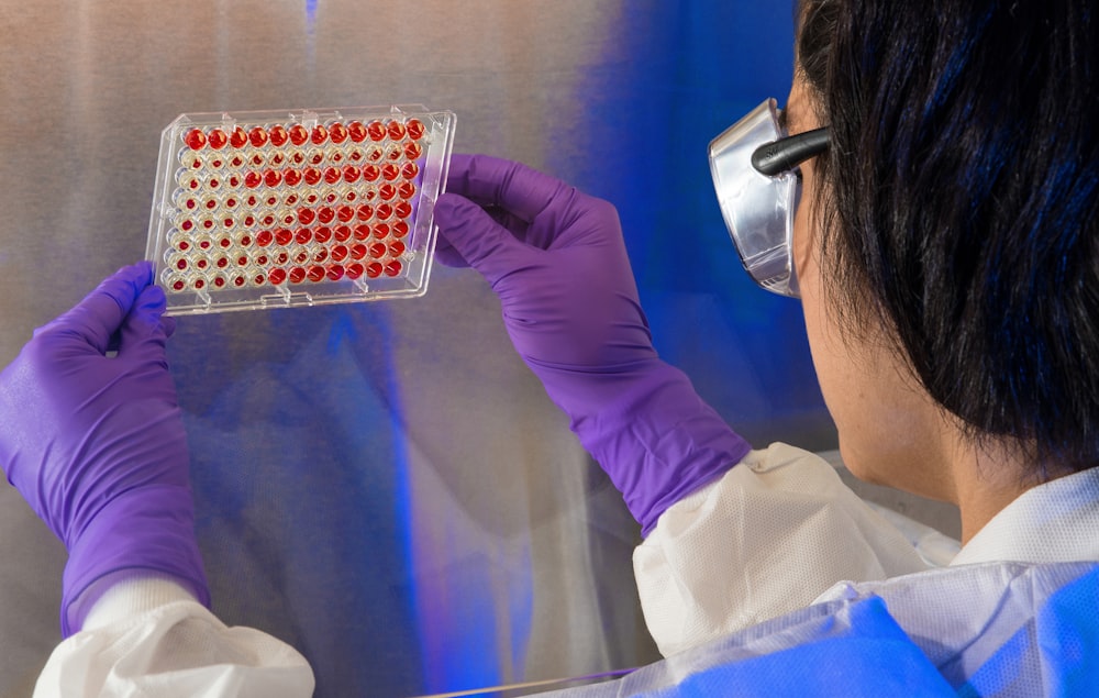 close-up photography of person holding a blood samples on clear plastic tray