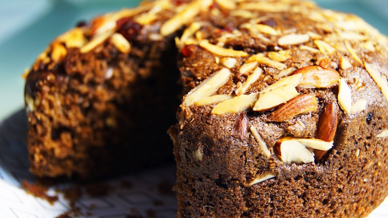 A round almond cake with a slice removed, topped with toasted slivered almonds, like a tarta de Santiago
