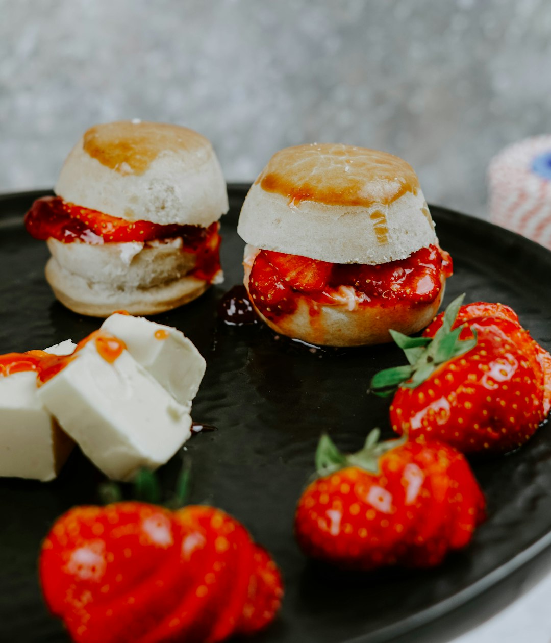 selective focus photography of strawberries and pastry on black plate