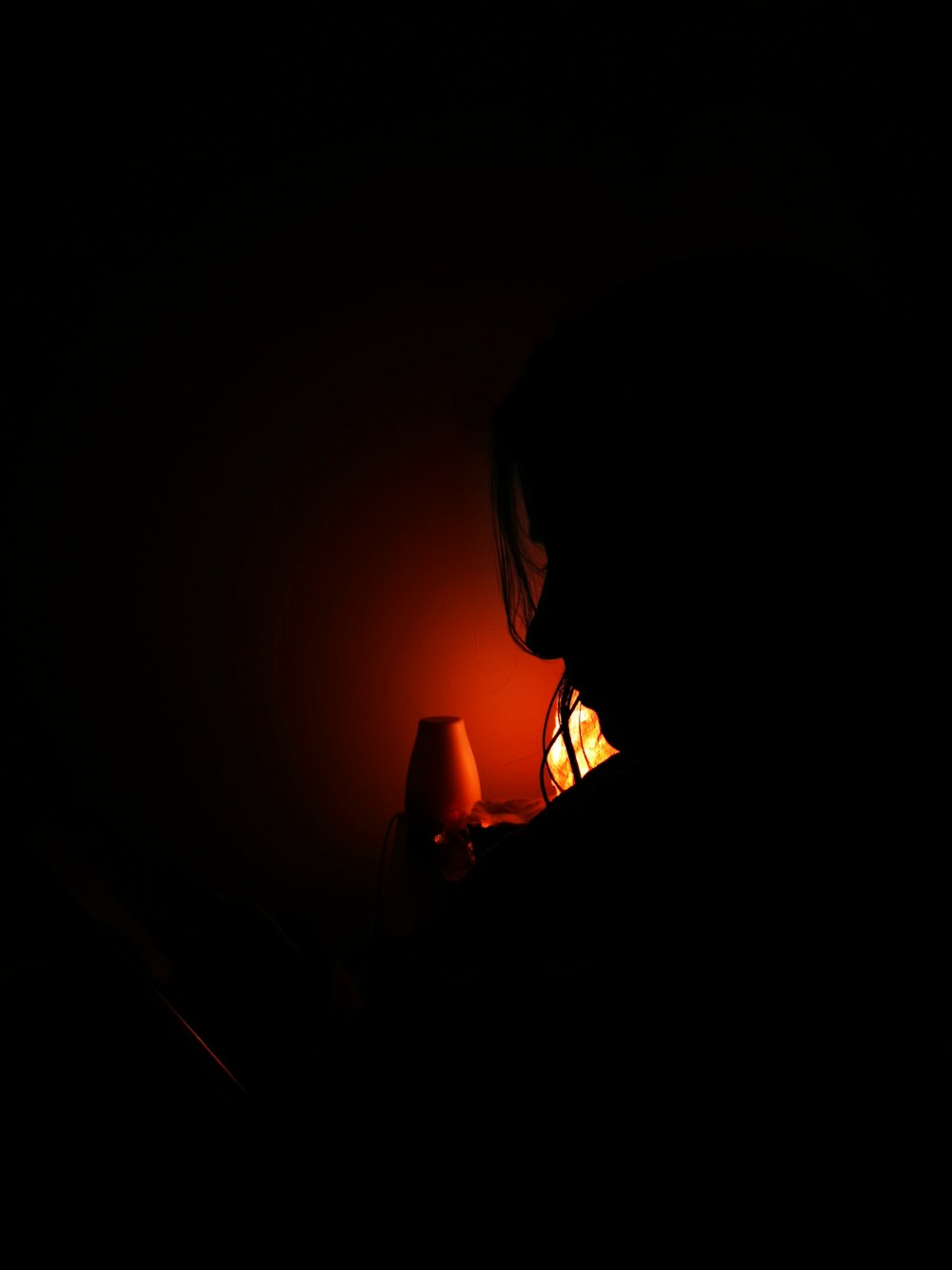 a person sitting in a dark room with a lamp