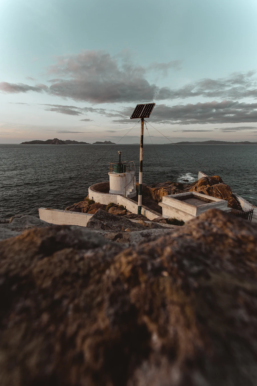 Standalone solar panel on a coastal cliff at dusk