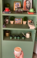A shelf filled with colorful books and a steaming cup of coffee.
