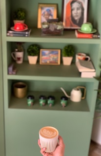 A shelf filled with colorful books and a steaming cup of coffee.