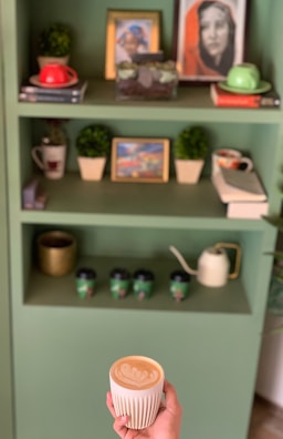 Smiling man with glasses holding a coffee cup, standing in front of a bookshelf filled with AI books.