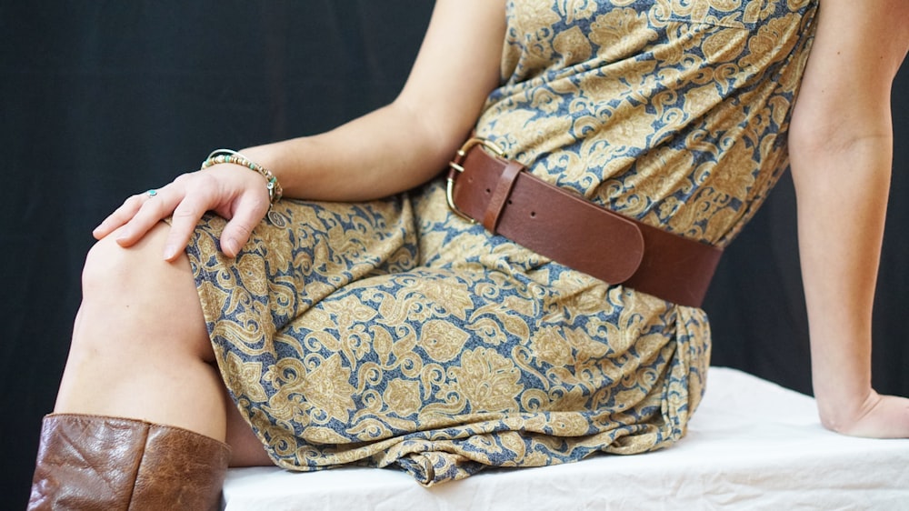 Femme en robe fleurie jaune et bleue assise sur une chaise