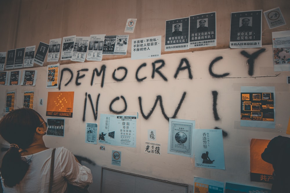 woman looking at wall with democracy now! text written in it