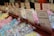 Multiple rows of sweet treats, each packaged in clear plastic bags and neatly organized, are displayed. Labels with product names like 'Sherbet Lemons' and 'Raspberry Bon Bon' along with prices are visible above each section. The sweets are in a variety of pastel colors including blue, pink, yellow, and green.
