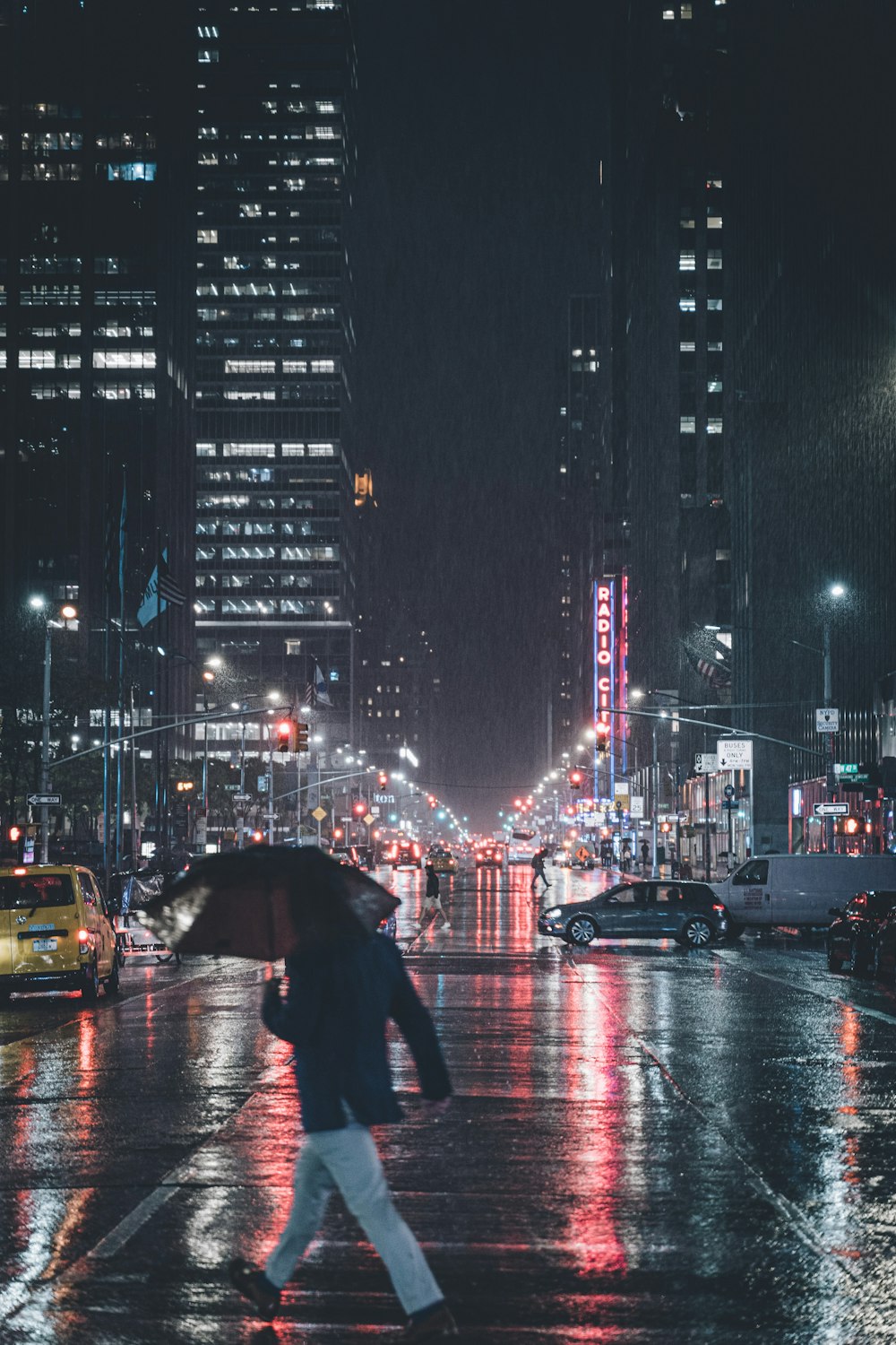 uomo che attraversa sulla strada sotto l'ombrello