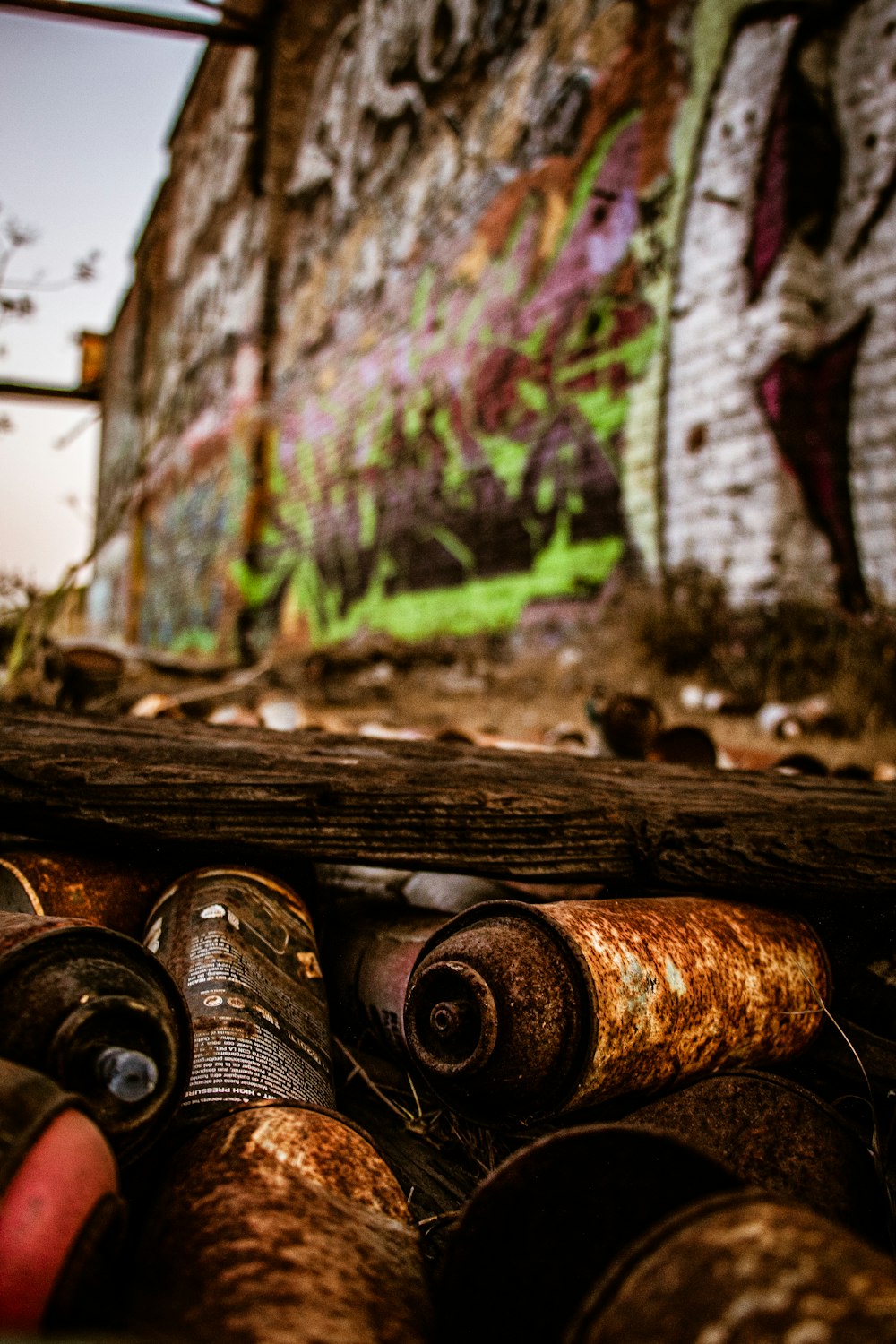 a bunch of old tin cans sitting in front of a graffiti covered wall