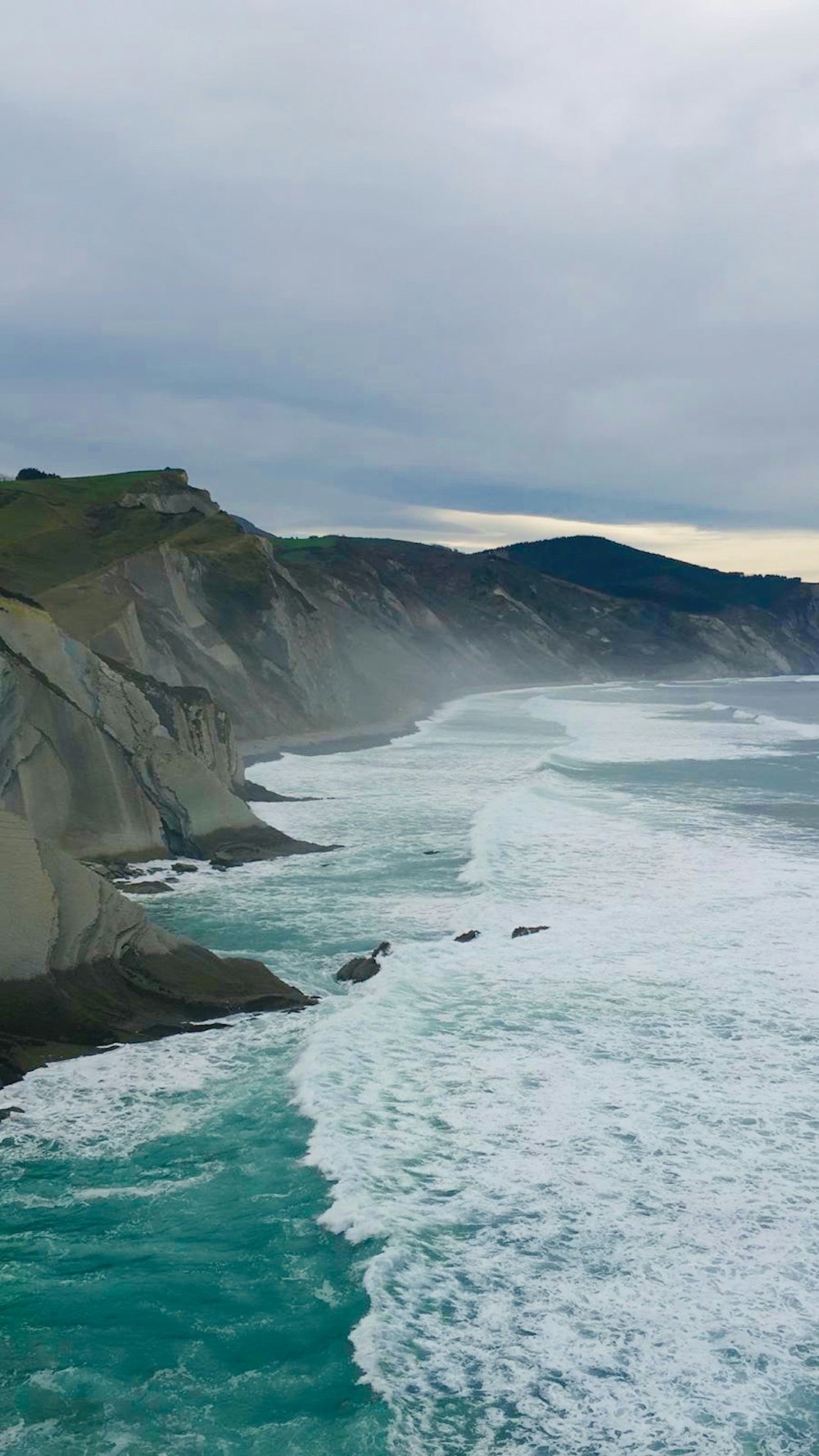 waves crashing on sea cliff during daytime