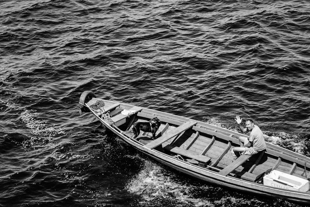 greyscale photography of man riding on boat