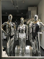 Close-up of elegant swimwear in burnt orange hues displayed on mannequins with tropical leaves background.