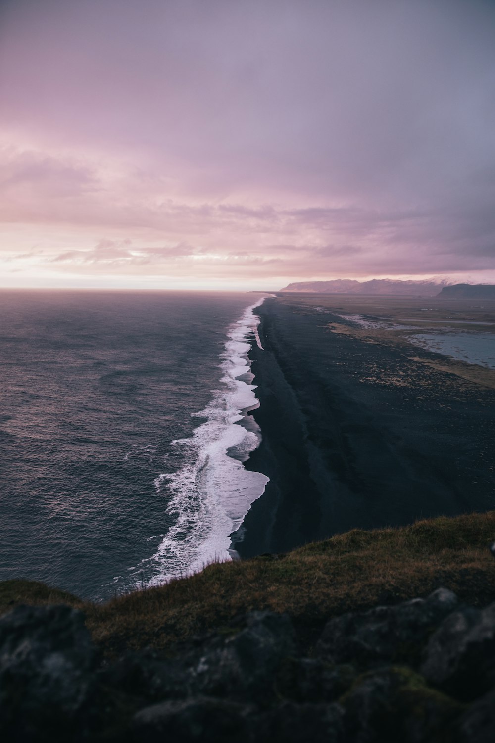 waves crashing on shore under cloudy sky during daytime