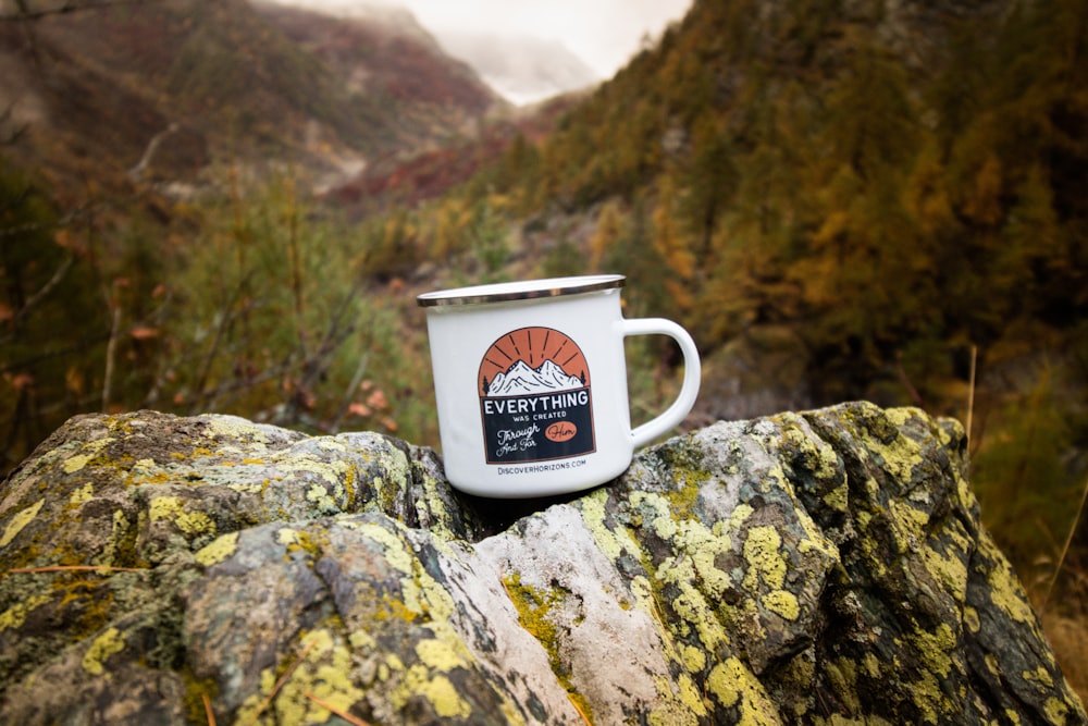selective focus photography of white and brown mug on rock during daytime