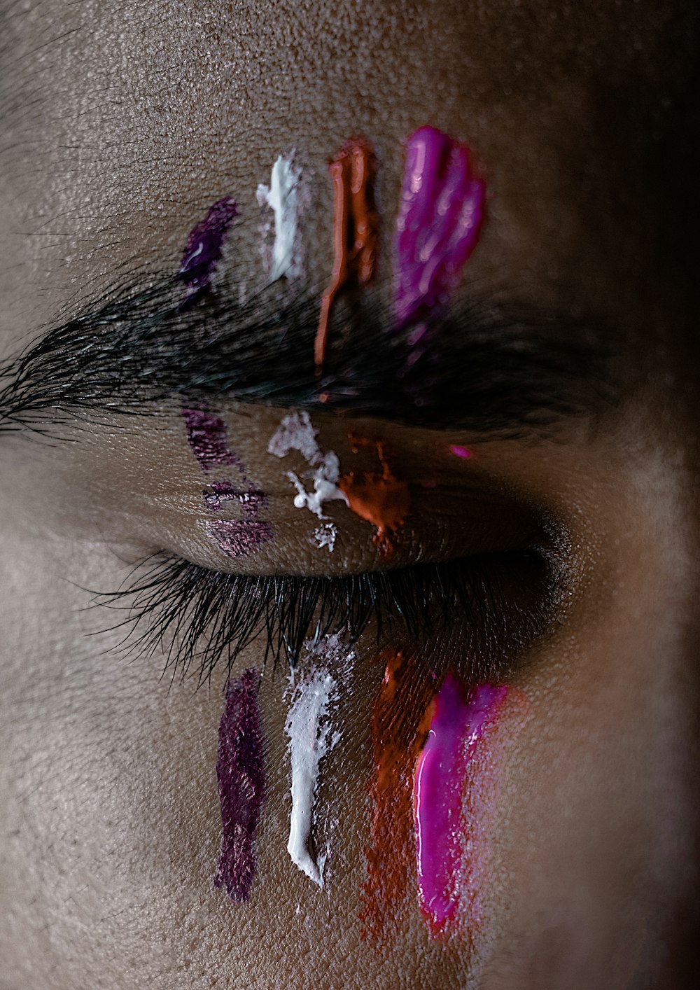 pink, red, white, and purple paints on man's eye