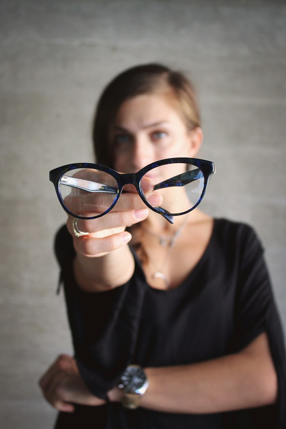 selective focus photo of eyeglasses hold by woman