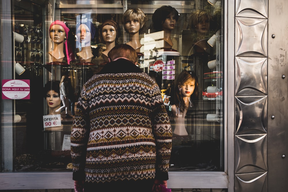 man leaning head in front of boutique's window