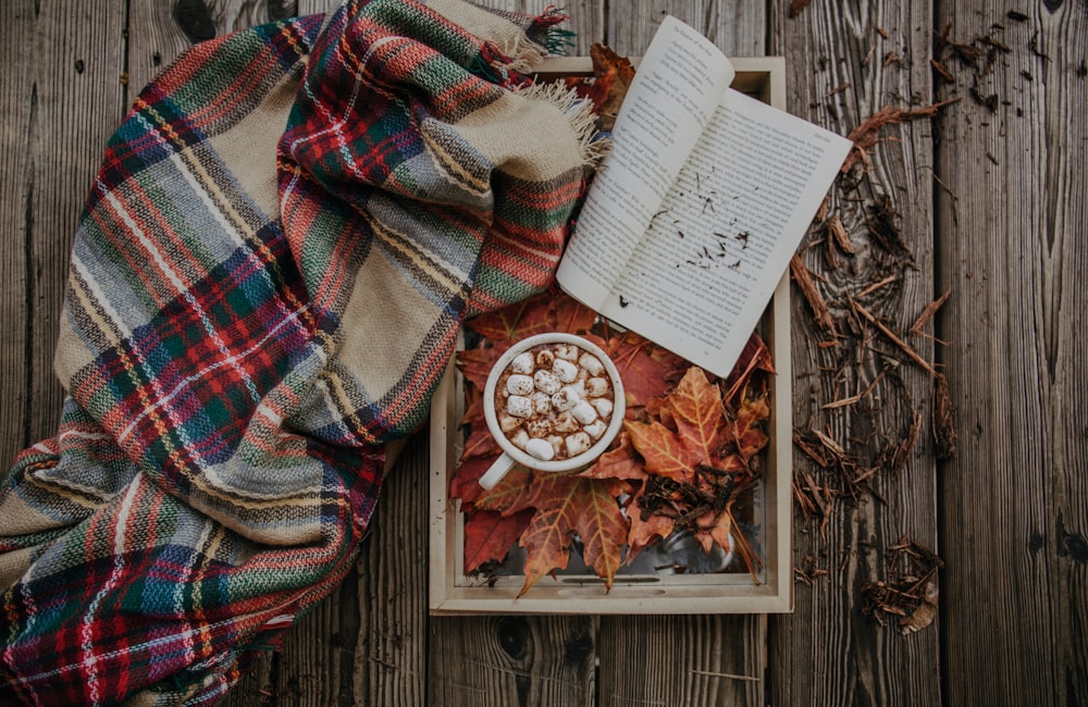 book on brown wooden tray beside blanket