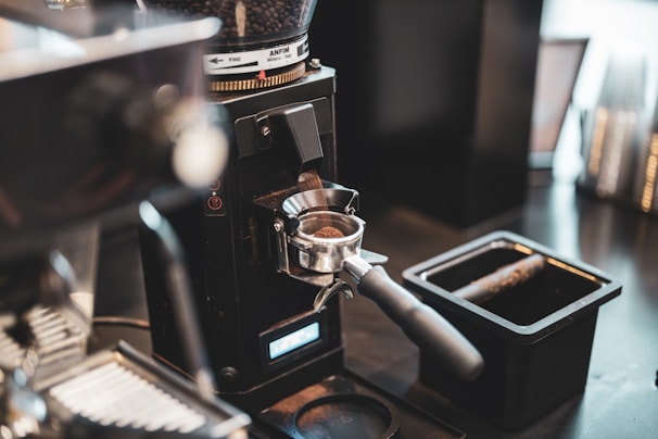 Close-up of a coffee grinder with freshly ground coffee spilling out.