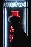 A lone figure silhouetted against a flickering neon sign, evoking isolation.