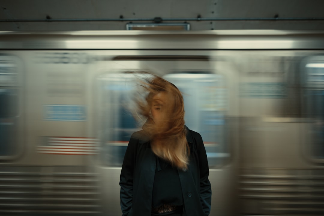panning photography of train with woman standing in front, model blown with a gust of wind by the subway train