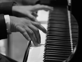 grayscale and selective focus photo of person playing piano