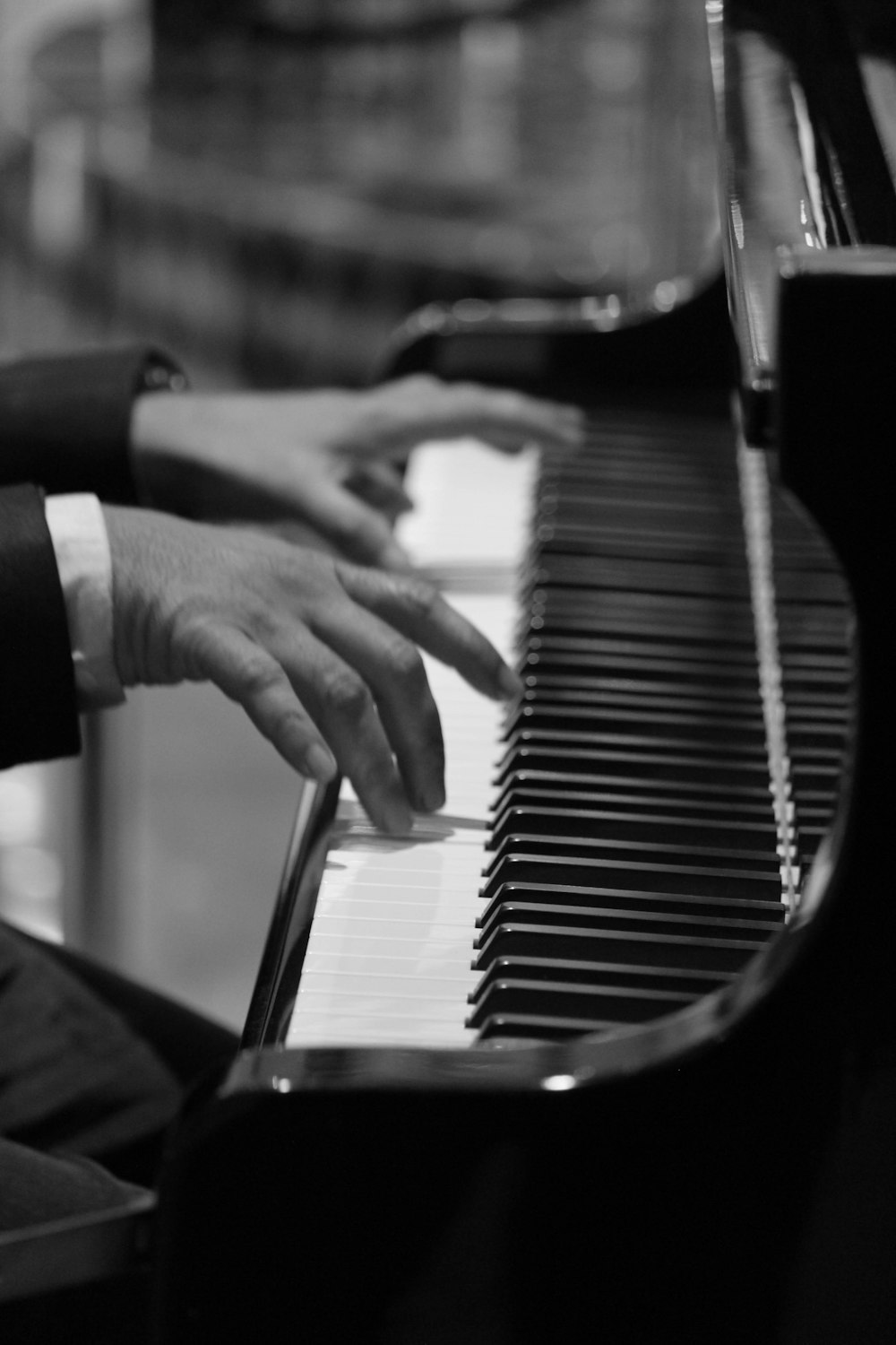 grayscale and selective focus photo of person playing piano
