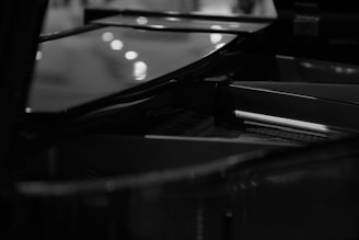 Black and white photo of a grand piano keyboard with soft natural light highlighting the keys.