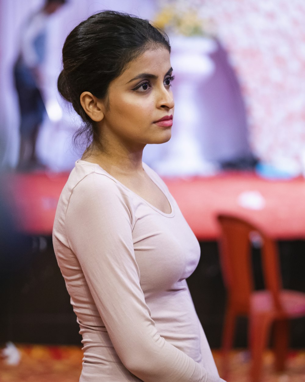 woman in pink top standing near red chair