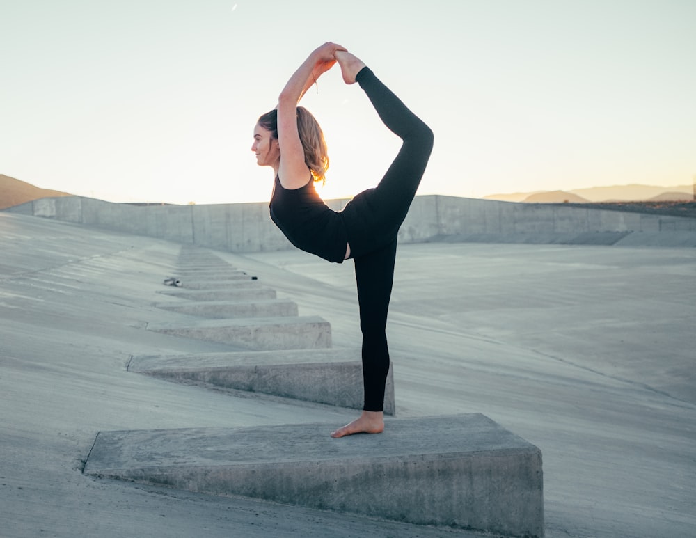 Foto einer Frau in schwarzem ärmellosem Hemd, die Yoga macht