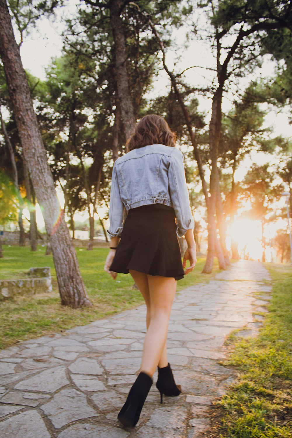 woman in blue denim jacket walking on concrete pathway