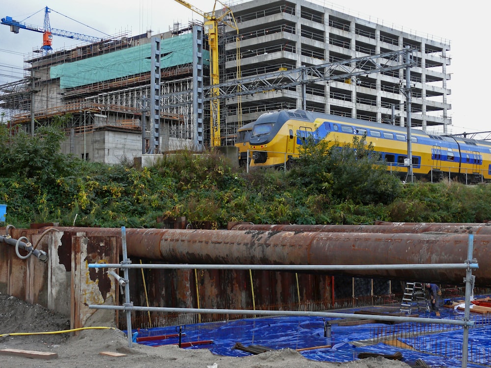 yellow and blue train passing by gray building