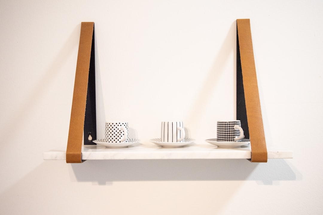 three white-and-black ceramic mugs on shelf