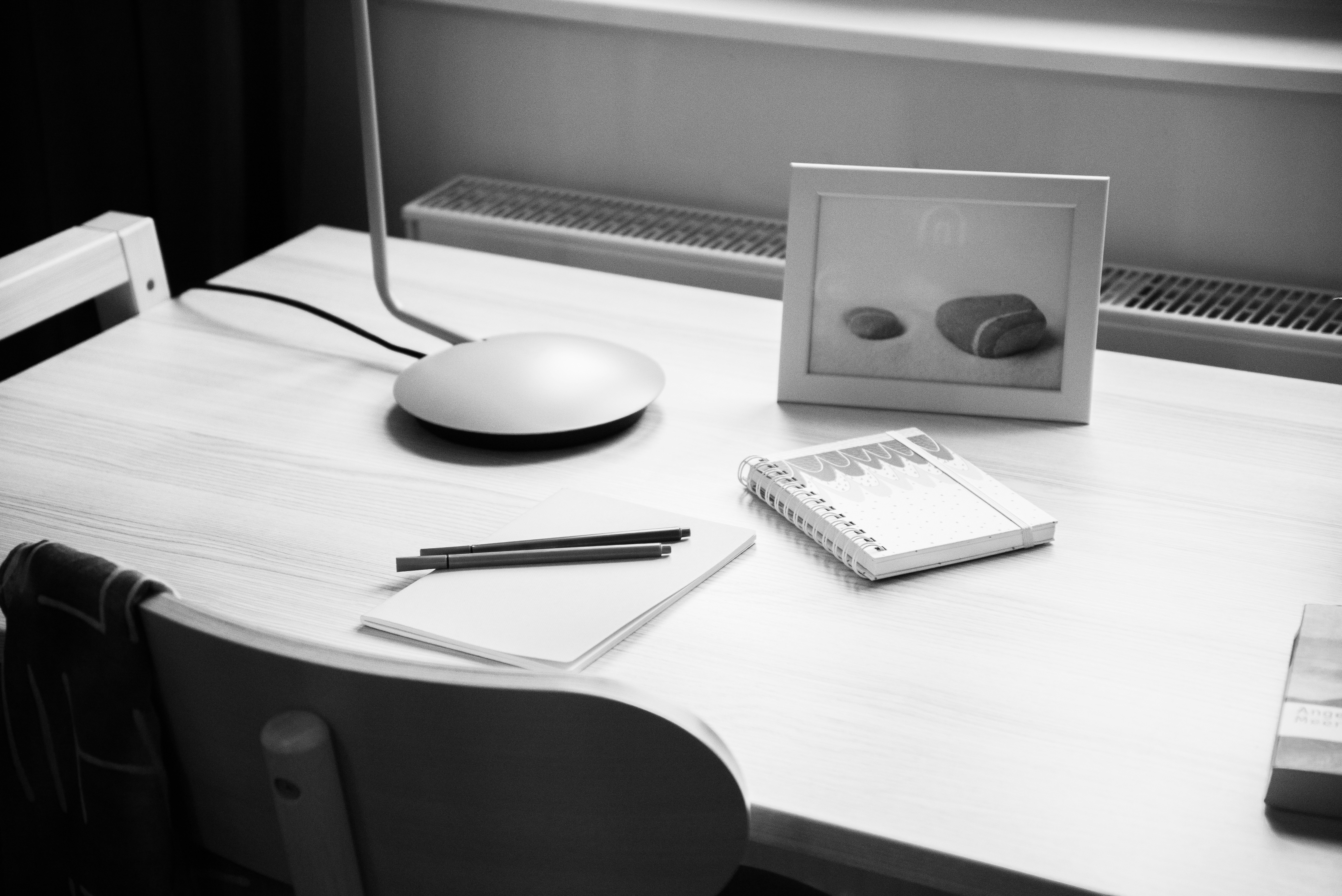 Minimalist wooden desk with a lamp, notebook, and stationery.