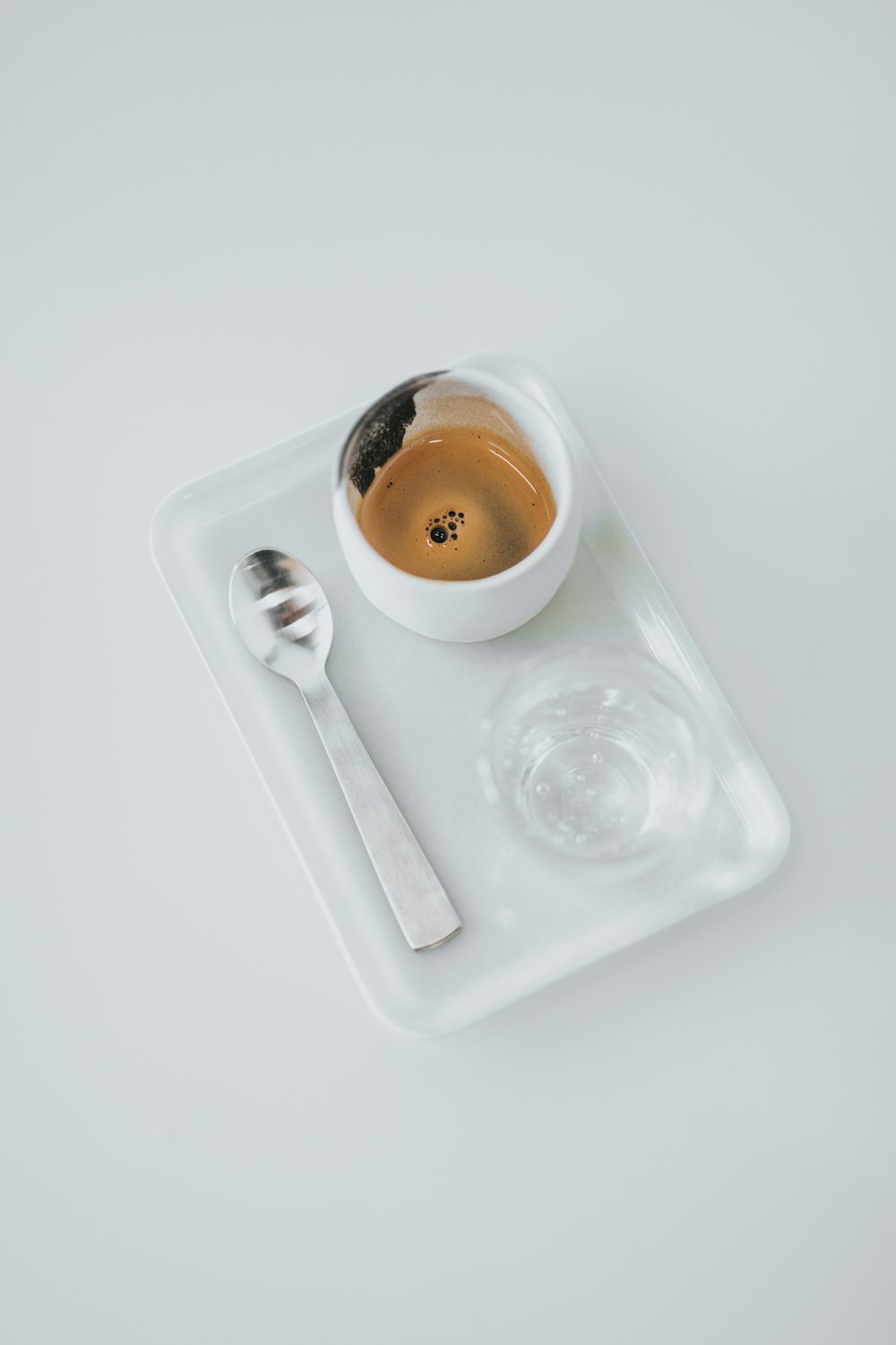 tazza bianca con cucchiaio con ciotola e vassoio