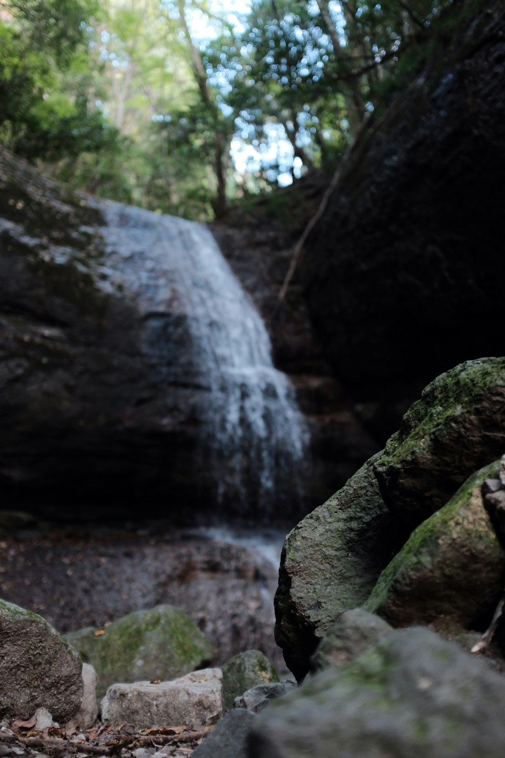 selective focus photo of stone with waterfalls in front