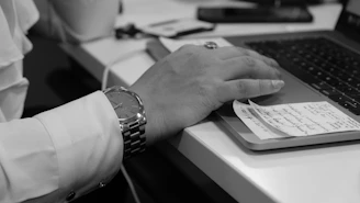 grayscale photo of person's hand on laptop