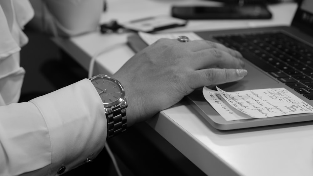 grayscale photo of person's hand on laptop