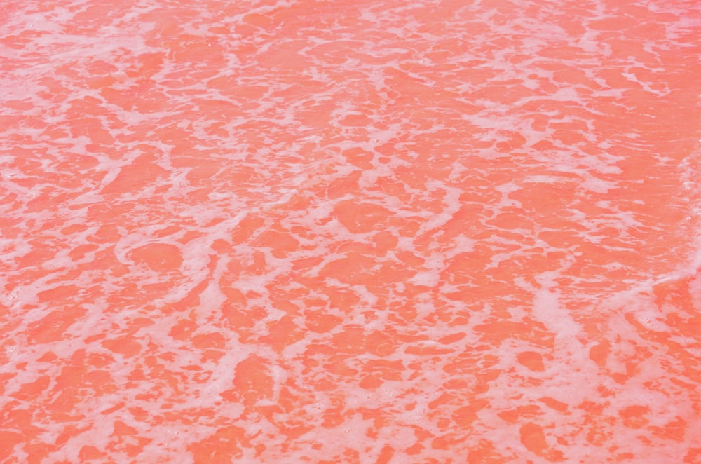 Ein orange-weißes Surfbrett, das auf einem Sandstrand sitzt