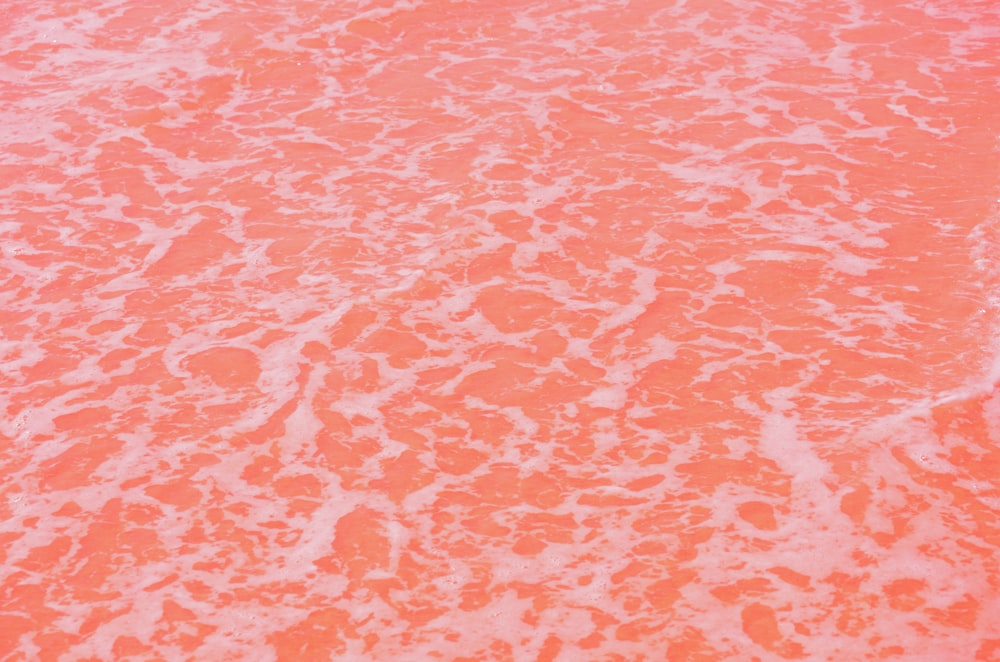 an orange and white surfboard sitting on top of a sandy beach