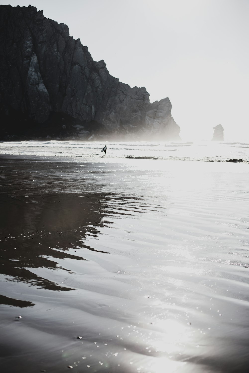 a person walking on a beach with a surfboard