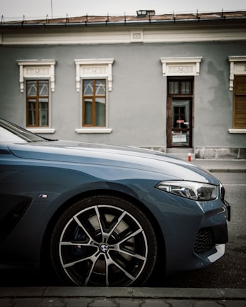 A sleek car parked in front of a vibrant Dakar street market.