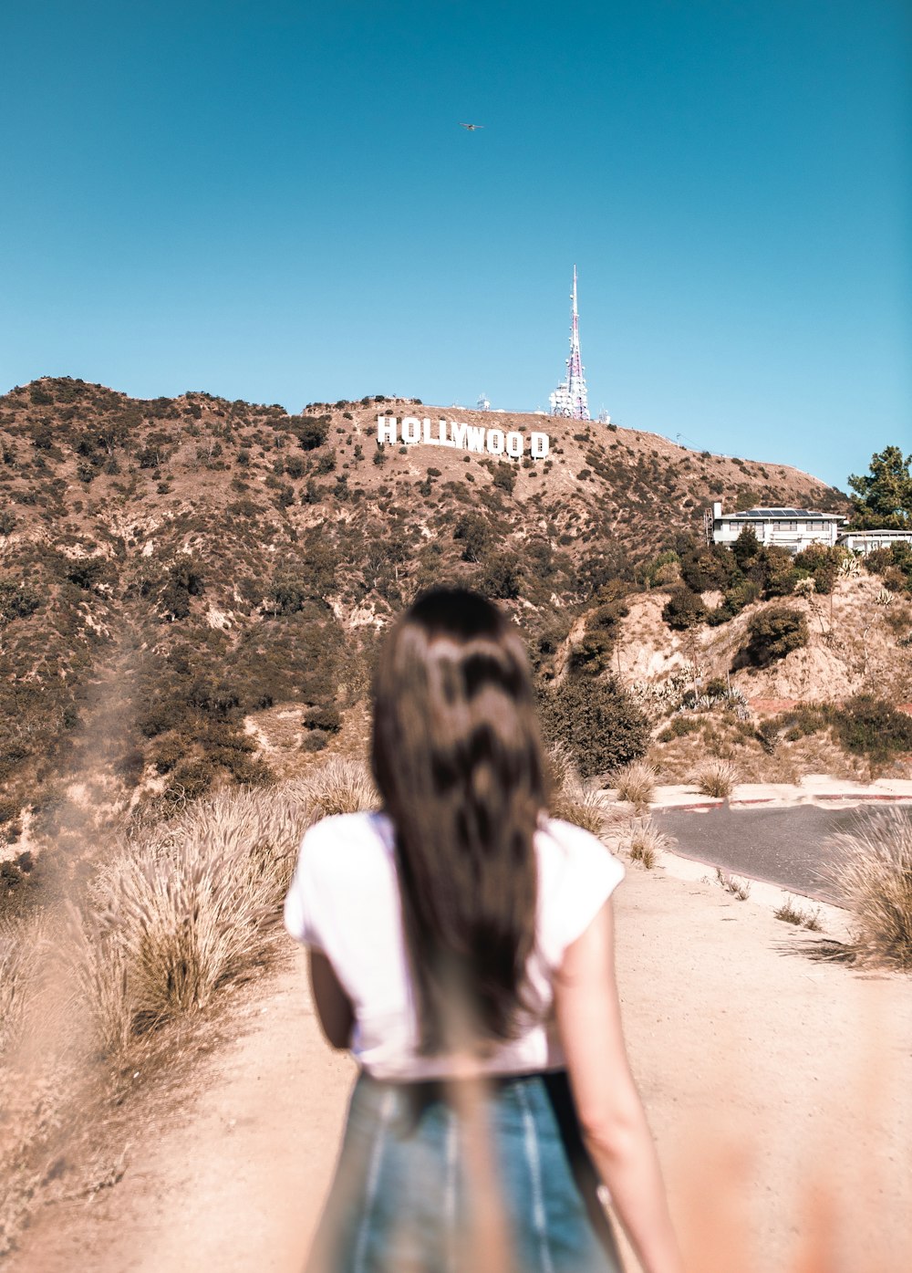 woman in white top standing beside road