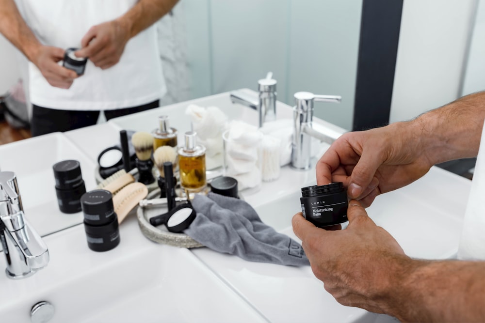 man holding black container reflecting on mirror