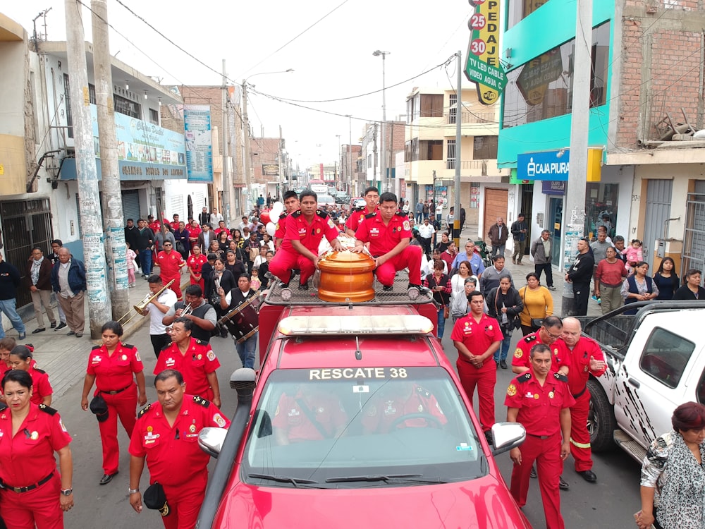 빨간 제복을 입은 남자들 옆에 빨간 트럭에 관이 놓여 있다