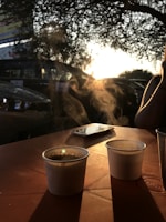 A warm sunset view with two cups of coffee on a balcony.
