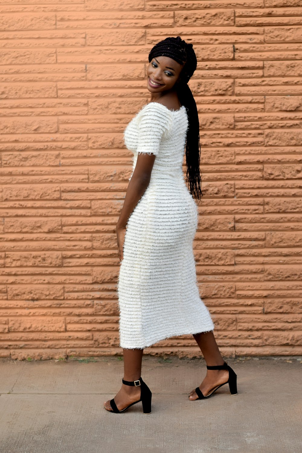 woman wearing white dress beside wall during daytime