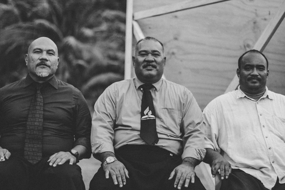 gray-scale photo of 3 man sitting on chair